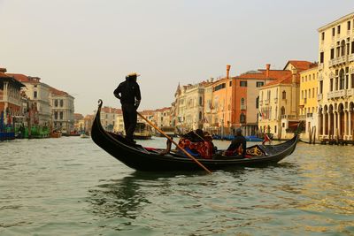 People in gondola on grand canal against sky in city