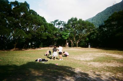 People relaxing in park against sky