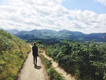 Rear view of man walking on road against mountains