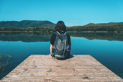 Rear view of man looking at lake against sky