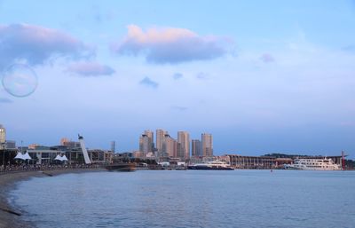 Sea by modern buildings against sky in city