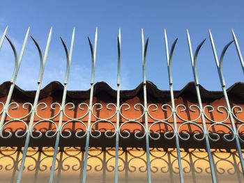 Low angle view of metal fence against sky