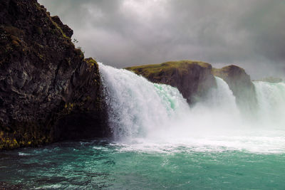 Scenic view of waterfall against sky