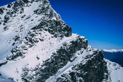 Scenic view of snowcapped mountains against clear blue sky