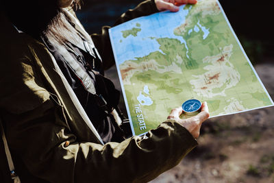 Midsection of woman holding map with compass