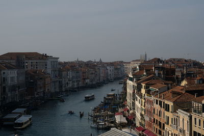 Boats in canal amidst buildings in city against clear sky