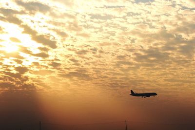 Airplane flying against sky during sunset