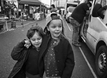 Portrait of happy siblings standing on road