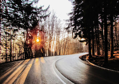 Road amidst trees against sky during sunset