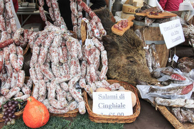 Salami for sale by dead wild boar at market