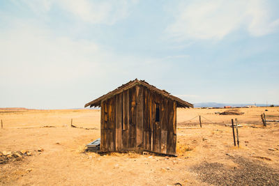 Abandoned wooden house on field against sky