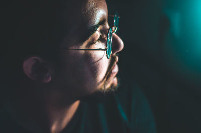 Close-up of man wearing eyeglasses looking away while at home