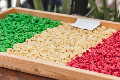 Fresh green, white and red orecchiette or orecchietta pasta drying under the sun on a wooden board