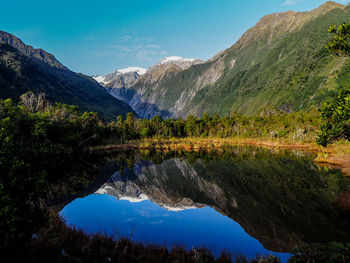 Scenic view of lake and mountains against blue sky