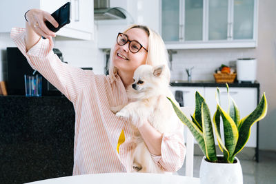 Laughing woman talking on video call with dog at home