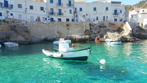 Sailboats moored on sea by buildings in city