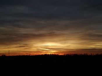 Silhouette landscape against dramatic sky during sunset