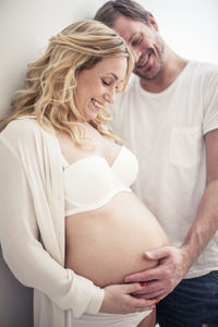 Happy man touching pregnant woman's stomach at home