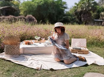 Rear view of woman sitting on mobile phone in field