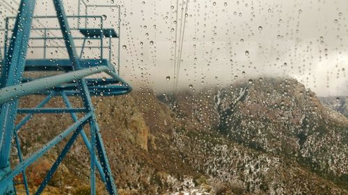 Observation point by mountains against sky seen through wet glass during monsoon