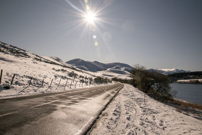 Road amidst snowcapped mountains against sky