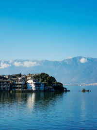 Scenic view of sea and buildings against blue sky