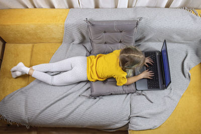 High angle view of girl using laptop on sofa at home