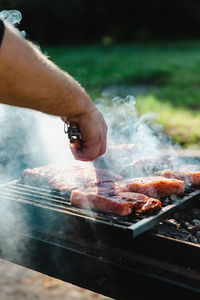Cropped hand of man preparing food on barbecue grill