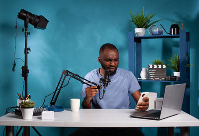 Side view of man using mobile phone while sitting on table