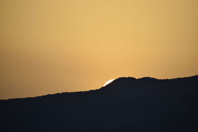 Scenic view of silhouette mountain against orange sky