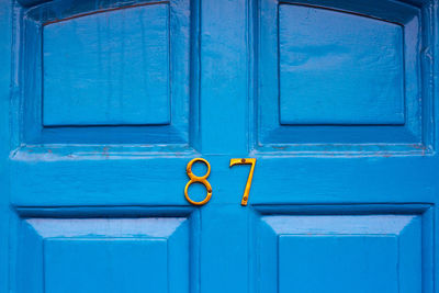 House number 87 on a blue wooden front door in london 