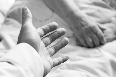 Cropped hand against senior woman lying on bed