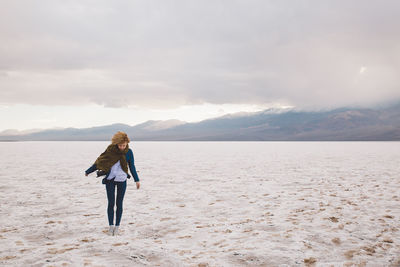 Woman standing on beach by sea against sky