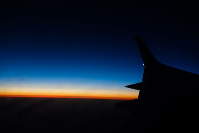 Close-up of airplane wing against sky at sunset