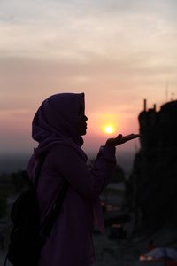 Midsection of woman standing against sky during sunset