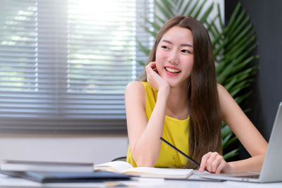 Portrait of a smiling young woman sitting on table