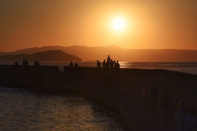 Silhouette people on beach during sunset