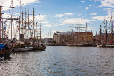 Sailboats moored at harbor against sky