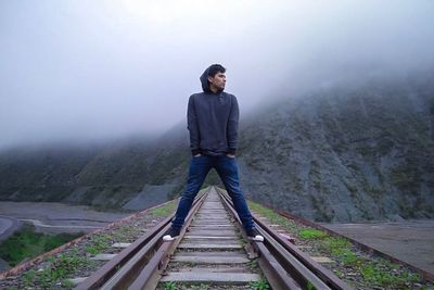 Full length of man standing on railroad track during foggy weather