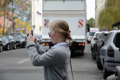 Side view of woman photographing on city street