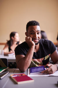 Portrait of young man using smart phone while sitting on table