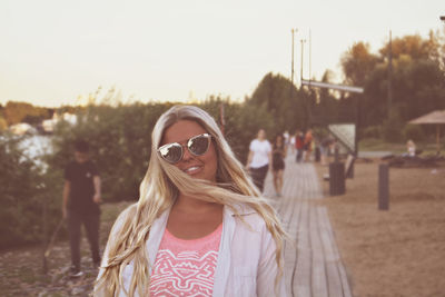 Portrait of young woman wearing sunglasses while standing on field