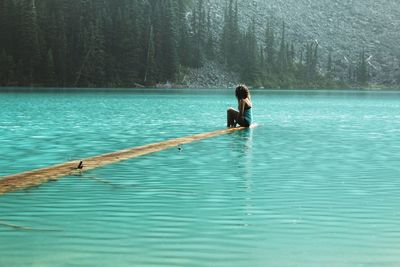 Man surfing in lake against trees in forest