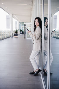 Portrait of beautiful chinese business woman using mobile phone in building office. technology