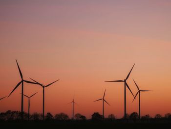 Silhouette wind turbine against sky during sunset