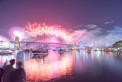 Firework display over river against sky at night