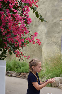 Side view of girl with pink flower against plants