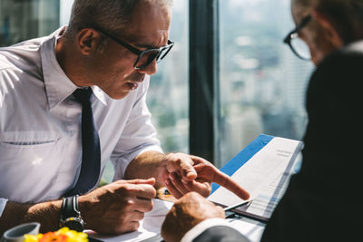 Man wearing eyeglasses having discussion with colleague in office