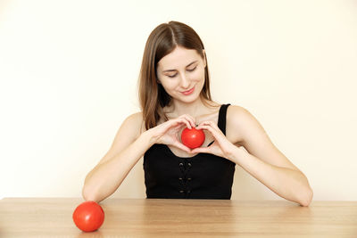 Young woman holding apple against white background