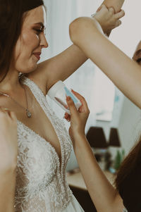 The maid of honor applies antiperspirant to the bride's armpits.